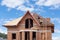 Construction crew working on the roof sheeting of new house made with bricks.