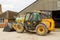 Construction digger loader in farm yard with barn