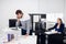 A construction engineer is solving some questions over the phone, while his colleague is working on her computer in the