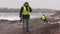 Construction engineer talking on cell phone and worker behind sorting paving bricks