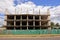 Construction of a gray paneled apartment building behind a fence near the road