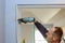 Construction handyman using air nail gun installing the interior door of apartment