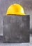 Construction hard hat at concrete cube or blocks near wall background texture. Yellow helmet