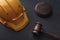 Construction helmet and judges gavel on black background. Top view. Construction law