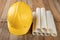 Construction helmet and roll of parchment with design. Construction engineer accessories on a wooden table