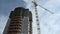 Construction of a high-rise building with a crane against a blue sky with clouds. Scene. Bottom view. grey multi-storey