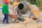 Construction labor unloads cement mixed with a wheelbarrow