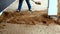 Construction laborer uses spade to move dirt near a house foundation.