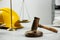 Construction and land law concepts. Gavel, scales of justice and hard hat on white table indoors, closeup