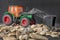 Construction machine vehicle, tractor toy model over gravel stones background.