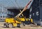 Construction machineries at work inside the metallic frame of a large commercial building under construction.