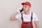 construction male worker In red working form and cap with cellphone in hand and communicates with customers isolated on