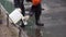 Construction man worker in orange uniform and helmet pours liquid to bottle.