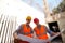 Construction manager and engineer dressed in work clothes and hard hats explore project documentation on the building