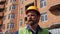 Construction manager in a yellow helmet with a beard and mustache speaks against the construction site. 4 k