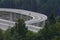 Construction of a modern overpass in mountains, high-speed concrete road in a mountainous area, a lot of tall trees on the slopes