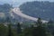 Construction of a modern overpass in mountains, high-speed concrete road in a mountainous area, a lot of tall trees on the slopes