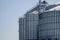 Construction of new cylindrical silos for grain storage. Metal silos are made of corrugated metal. A row of hand winches lifts the