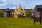 Construction of a new wooden orthodox church in a spring field with authentic ancient mills and a horse in foreground