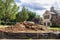 Construction  - Pile of dirt in vacant lot behind black plastic fence in upscale neighborhood with parts of adjacent houses and