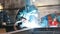 Construction plant. A man worker close up a helmet and using a welding machine