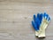 Construction rubberized gloves on a bright  wooden background. Blue protective rubber gloves for construction and operation with c