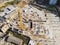 Construction site aerial view. Mall building base with solid concrete pillars. Heavy machinery and high tower crane