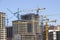 Construction site background. Hoisting cranes and new multi-storey buildings. tower crane and unfinished high-rise building. many