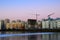 Construction site with construction cranes and tall houses on the background of the evening sunset and frozen lake. Cold