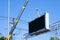 Construction site crane is lifting a led signboard Blank billboard on blue sky background for new advertisement