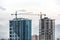 Construction site, cranes and multi-storey unfinished buildings over mist mountain background. Development building construction