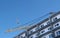 Construction site with cranes on sky background. The Builder works on the roof of a multi-storey building.