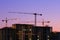 construction site at dusk after sunset. Construction of a multi-storey building. Silhouettes of construction cranes