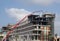 Construction site with a large red telescopic crane and building workers building a large modern hotel complex in cyprus