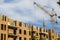 Construction site of a new apartment high building with tower cranes against blue sky. Residential area development. Real estate p