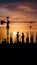 Construction site silhouettes at sunset, including crane and workers