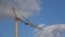 Construction tower crane, against blue sky with moving white clouds.