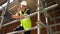 Construction worker on building site standing on scaffolding thumbs up to camera