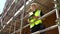 Construction worker on building site standing on scaffolding writing on a clipboard