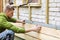 Construction worker checking level of house wood facade