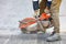 A construction worker cuts old asphalt with a portable petrol saw and a diamond cutting disc