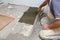 The construction worker evenly spreads the surface of the stairs with cement adhesive mass using a special hand tool.