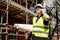 Construction worker, foreman or architect on construction site talking on his cell phone and holding rolled building plans