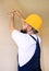 Construction worker and handyman works on renovation of apartment. Builder using yellow screwdriver screws steel screw out of wall