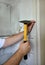 Construction worker and handyman with yellow hammer strikes and nails a nail into wooden wall of kitchen door at construction site