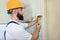 Construction worker and handyman with yellow hammer strikes and nails a nail into wooden wall of kitchen door at construction site