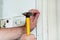 Construction worker and handyman with yellow hammer strikes and nails a nail into wooden wall of kitchen door at construction site