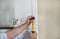 Construction worker and handyman with yellow hammer strikes and nails a nail into wooden wall of kitchen door at construction site