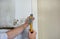 Construction worker and handyman with yellow hammer strikes and nails a nail into wooden wall of kitchen door at construction site