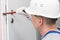 A construction worker in a helmet opens the front door with a special tool